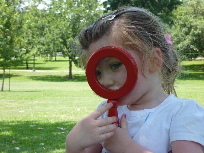A littel girl with a magnifying glass.