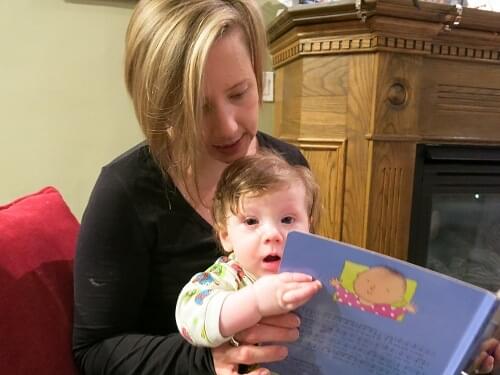 Mom and 9 month old reading a book together.